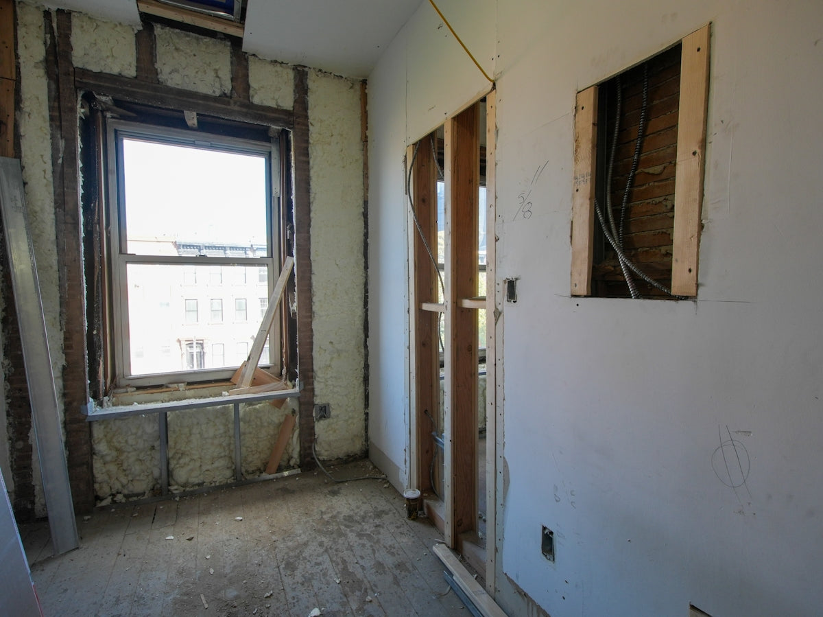Interior room undergoing renovation with exposed walls and window.