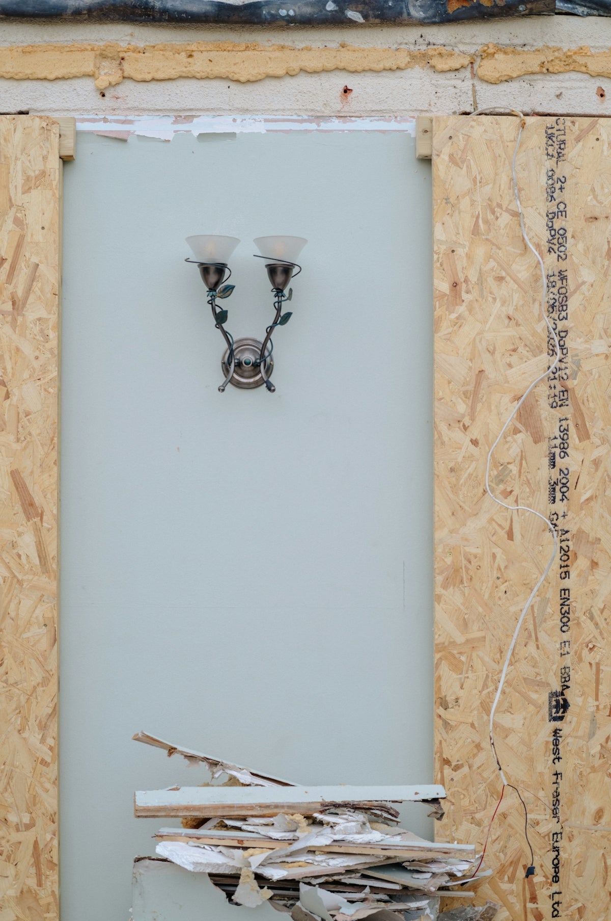 Wall sconce on blue wall amidst renovation debris